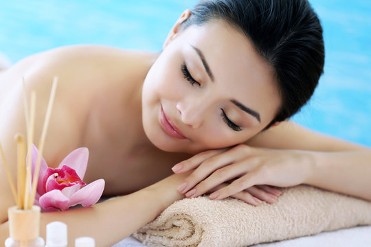 Spa concept. Young pretty woman relaxing on blue background, close up