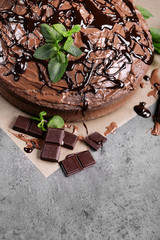 Decorated chocolate pie with mint and chocolate bar on grey table