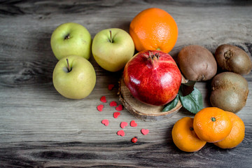 assorted tangerine kiwi apple lemon and pomegranate on Rustic Wooden Table