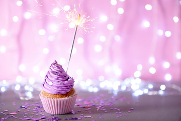 Cupcake with purple cream icing and sparkle on a glitter background