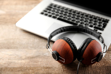 Laptop and earphones on wooden background