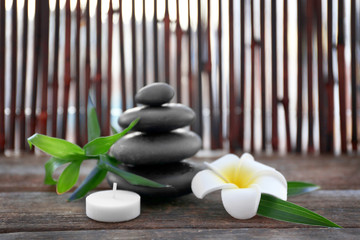 Spa stones with bamboo, candle and tropical flower on wooden background