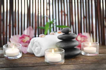 Spa stones with towel, candles, bamboo and pink orchids on wooden background