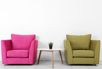 Living room interior with pink, green armchairs, white table and plant on white wall background