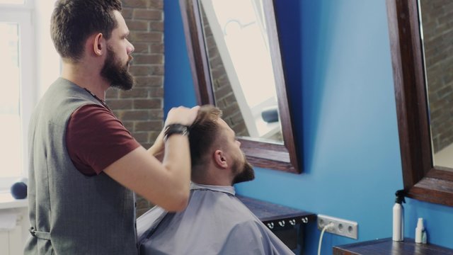 Friendly hairdresser dries the hair dryer hair man
