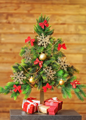 A handmade green Christmas tree and presents on wooden wall background