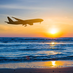 Fototapeta na wymiar airplane over a sea coast sunset