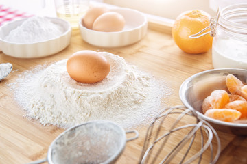 Baking cake in kitchen - dough recipe ingredients (eggs, flour, milk, sugar) with fruit on wood table, background for patisserie or kitchen