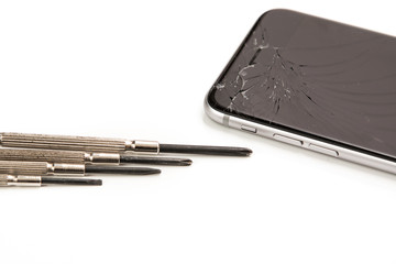 Broken smartphone and small screwdrivers for repair
