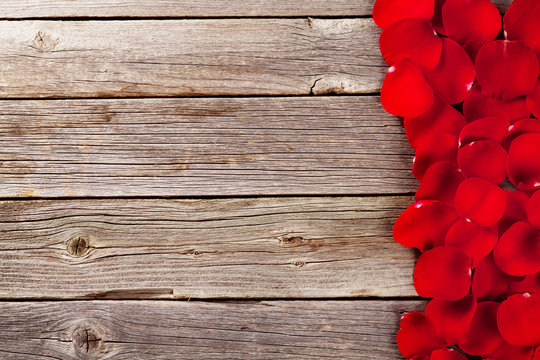 Red rose petals over wooden background