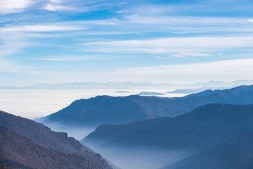 Fototapeta na wymiar Blue toned mountain silhouette and foggy valleys in winter