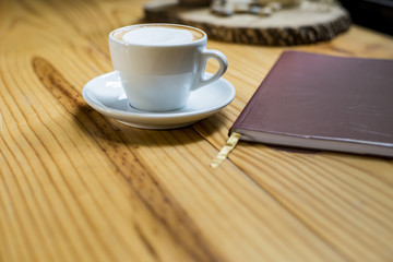 notebook with cup of coffee on wooden desk