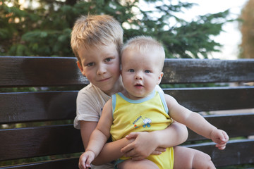 funny little children brothers sitting on bench 