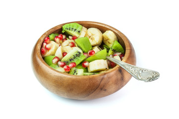Fruit salad with banana, kiwi and pomegranate in a wooden bowl, isolated on white background