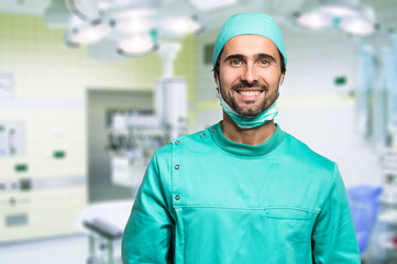 Smiling surgeon crossing his arms while standing in a surgical room