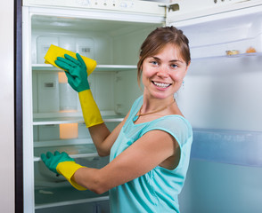 Housewife washing fridge with detergent