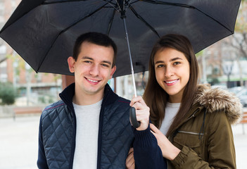 couple walking under umbrella at autumn day