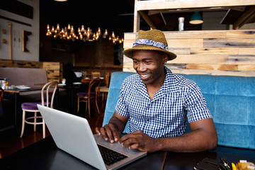 African american man sitting at a cafe and working on a laptop