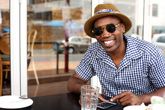 Happy african american man sitting at cafe with mobile phone