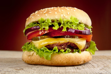 Big cheeseburger isolated on red background - obrazy, fototapety, plakaty