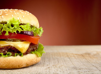 Big cheeseburger cropped on red background - obrazy, fototapety, plakaty