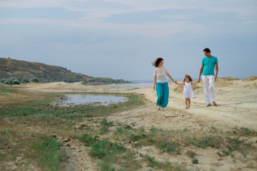 Happy family of three having fun walking along the beach