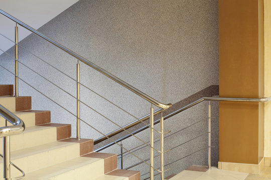  Brown staircase with metal railing, gray wall