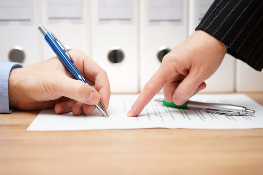business woman is pointing where to sign on document, with docum