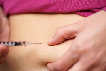 woman with diabetes  give insulin shot by syringe into belly