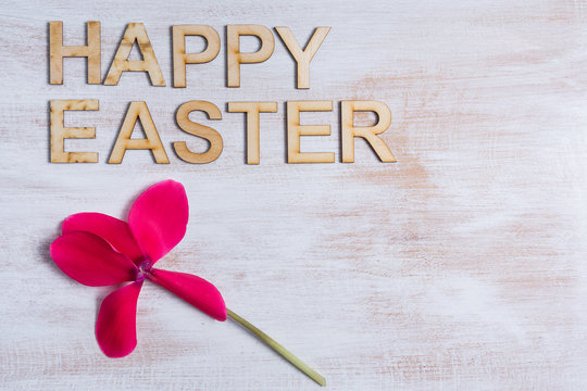 Cyklamen i napis happy easter na tle drewnianej białej deski