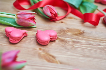Heart-shaped macarons with flowers and ribbon on a wooden table. Creative decoration for Valentine's Day