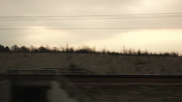 View of suburb landscape through railway train window in motion in winter morning.