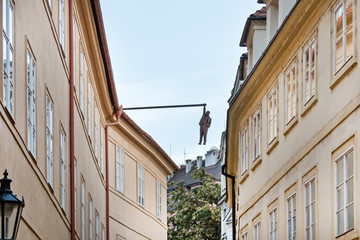 Fototapeta na wymiar The narrow street with houses and hanging sculpture of a man