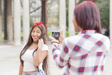 Young woman taking pictures of her friends in the park.