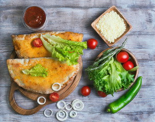 Closed pizza calzone on a light wooden background