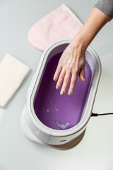 Fototapeta premium Female hands in a paraffin wax bowl
