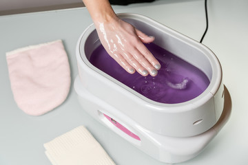 Female hands in a paraffin wax bowl - obrazy, fototapety, plakaty