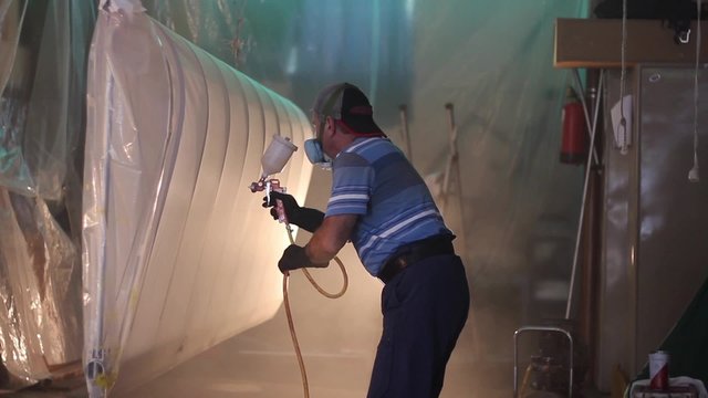 Man painting with airbrush the wing of airplane