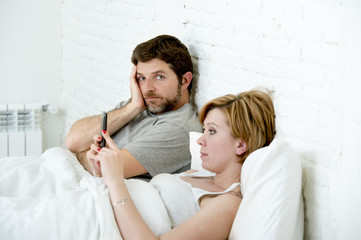 couple in bed husband frustrated upset unsatisfied while wife using mobile phone
