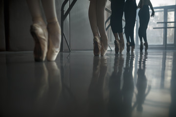 Ballet dancers stands by the ballet barre.