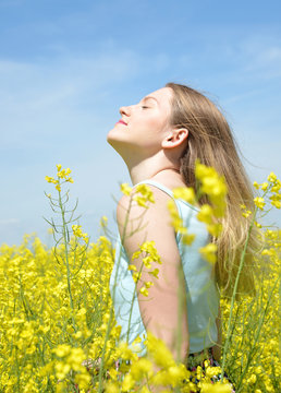 Young happy woman on blooming rapeseed field
