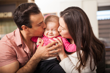 Parents kissing baby at the same time