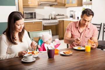 Parents and baby having breakfast at home
