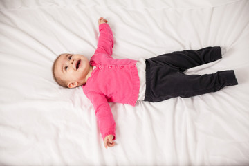 Happy baby girl lying on a bed