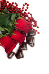 Red roses and candies in a shape of a heart isolated