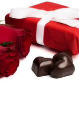Red present box with white ribbon, red roses and candies