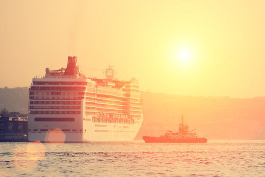 Large passenger ships at sunset next to the industrial ship