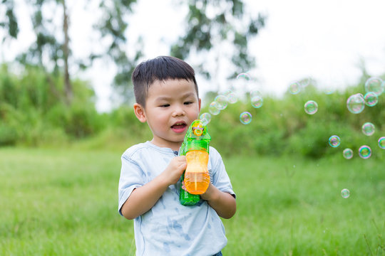 Little boy play bubble blower at park