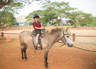 Little boy riding training horse