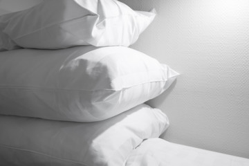 Pile of white pillows lying on empty bed